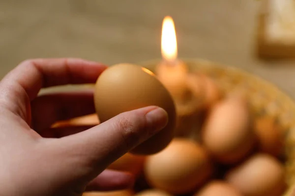 手拿着鸡蛋光的烛光 粗俗的背景 帕斯卡鸡蛋 皮桑卡收集背景下的蛋 准备度假 牛皮纸传统 精神上的 — 图库照片