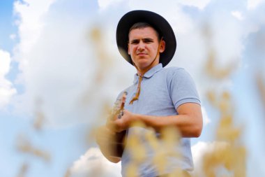 Ciddi bir müzisyen. Genç, güzel beyaz bir adam dışarıda ukulele çalıyor. Yakışıklı hippi, doğada gitar çalıyormuş. Kovboy şapkalı bir erkek gülümseyerek gitar çalıyor..