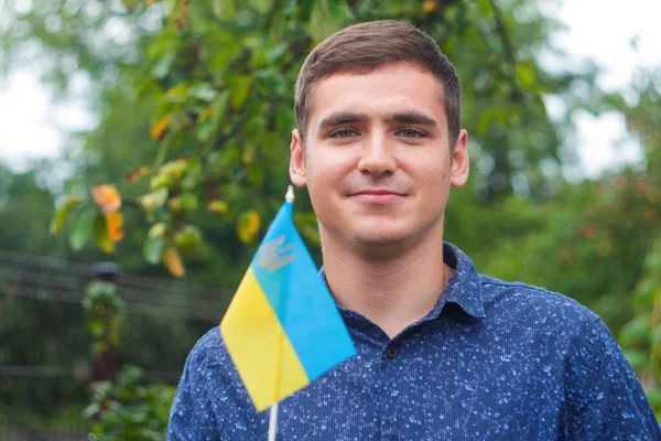 Hombre ucraniano. Joven hombre sonriente sosteniendo bandera ucraniana. No hay guerra. Apoyo a Ucrania. Espíritu patriótico levantando la mano de la bandera de Ucrania. Ucrania de la libertad. Fondo de la naturaleza. Personas, personas — Foto de Stock
