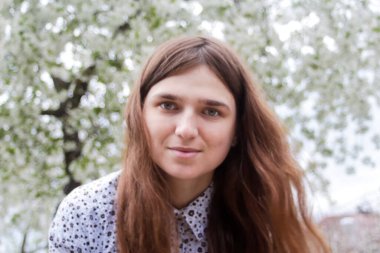 Çiçek açan ağaçların etrafındaki romantik aroma parkında açık havada çekilmiş uzun saçlı beyaz kadın portresi. Romantik bir portre. Odaklanamıyorum.