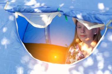 Sivrisinek önleyici bir pencerenin arkasındaki mavi bir çadırda rahatça oturan kız dışarıya bakıyor. Şapkalı genç kız portresi. - Günaydın. Gezgin çocuk. Güneş parlaması. Odaklanamıyorum.