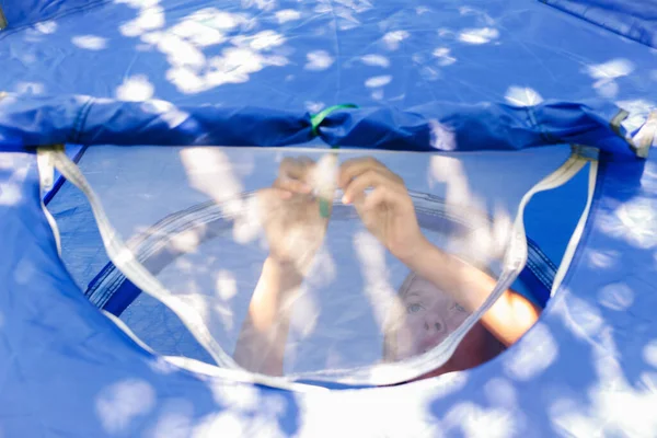 Sivrisinek önleyici bir pencerenin arkasındaki mavi bir çadırda rahatça oturan kız dışarıya bakıyor. Genç kızın portresi. - Günaydın. Pencereyi aç ya da kapat. İyi geceler. Mavi çadır. Odaklanamıyorum.