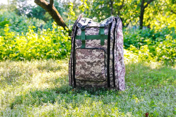 Askeri sırt çantasından çık. Ağacın yanındaki yeşil çimlerin üzerinde ordu çantası. İngiliz ordusunun sırt çantasında askeri kamuflaj malzemesi. Yakın plan. Turist yaz yürüyüşçüsü. Trip konsepti. Odaklanamıyorum.
