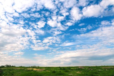 Küçük beyaz bulutlar ve yeşil çayır ile mavi gökyüzü arkaplanı. Bulutlu panorama mavi gökyüzü arkaplanı. Bulanık parça arkaplanı. Meteoroloji. Odaklanamıyorum