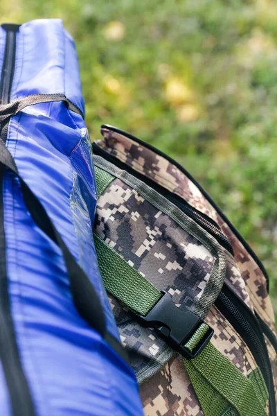 Askeri sırt çantası ve mavi çadır ya da uyku tulumu. Ağacın yanındaki yeşil çimlerin üzerinde ordu çantası. Askeri kamuflaj ordu sırt çantası. Turist yaz yürüyüşçüsü. Yaz. Yakın plan. Odaklanamıyorum