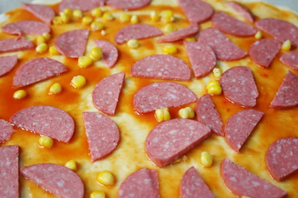 Hamur üzerinde pizza için Defocus yakın çekim malzemeleri. Kırmızı domates sosu, sosis, tatlı mısır. Ev yapımı İtalyan pizzası. Margarita üssü. Ev mutfağı. Üst Manzara. Odaklanamıyorum.