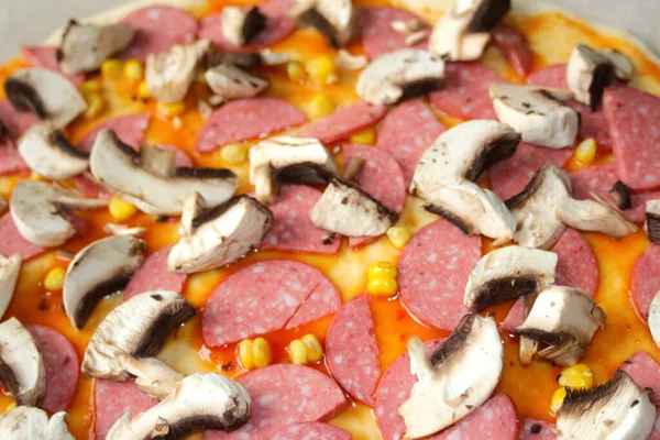 Hamur üzerinde pizza için Defocus yakın çekim malzemeleri. Kırmızı domates sosu, sosis, tatlı mısır. Ev yapımı İtalyan pizzası. Ev mutfağı. Üst Manzara. İtalyan mutfağı geçmişi. Odaklanamıyorum.