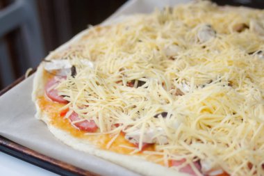 Defocus, taze rendelenmiş mozzarella peynirli tüm pizzayı yakından çek. Defocus hamur üzerinde pizza malzemelerini bulanıklaştırdı. Uzayı kopyala İtalyan mutfağı geçmişi. Arkaplan. Margarita. Odaklanamıyorum.