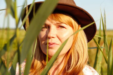 Defocus, sazlığın ve otların yanında güzel sarışın bir kadının portresinin hemen dışında. Sanat gölgeleri ekin. Meadow 'daki kovboy kız. Akıl sağlığı, sessizlik. Kırsal kesimde, sağlıkta. Odaklanamıyorum.