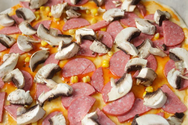 Hamur üzerinde pizza için Defocus yakın çekim malzemeleri. Kırmızı domates sosu, sosis, tatlı mısır. Ev yapımı İtalyan pizzası. Margarita üssü. Ev mutfağı. Üst Manzara. İtalyan mutfağı. Odaklanamıyorum.