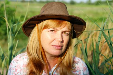 Defocus, doğa arka planında güzel sarışın bir kadının dış portresini yakından çek. Sanat gölgeleri ekin. Meadow 'daki kovboy kız. Akıl sağlığı, sessizlik. Kırsalda, sağlıkta, kaygısızlıkta....