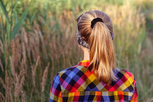 フォーカスポニーテールのヘアスタイル 10代か10代の少女が自然を背景に歩いて立ち上がる 子供の女の子 緑の牧草地 Z世代 バンダナ ライフスタイル 集中できない — ストック写真