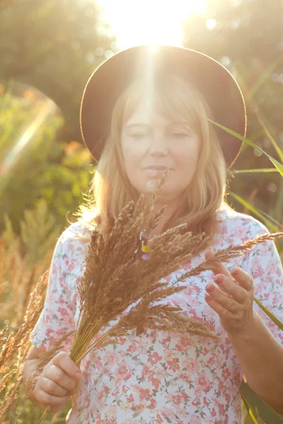 Defocus, doğa arka planında güzel sarışın bir kadının dış portresini yakından çek. Elinde pampa otları tutan bir kadın. Akıl sağlığı, açık hava. Yaşam tarzı, sağlık, boho. Güneş. Odaklanamıyorum.