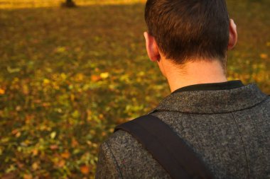 Sonbaharda ormana bakan üzgün, yakışıklı bir adamın Defocus 'un yakın plan portresi. Parkın, ormanın ve caddenin doğasında bir portre. Üzücü. Arkadan bak. Odaklanamıyorum.