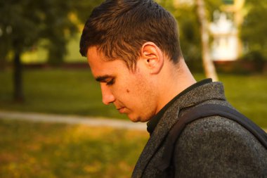 Sonbaharda ormanda parka bakan üzgün, yakışıklı bir adamın defocus portresi. Parkın, ormanın ve caddenin doğasında bir portre. Üzücü. Akıl sağlığı. Odaklanamıyorum.