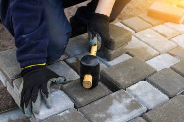 Defocus Paver ustası. İnsan katman katman taş döşeyebilir. Profesyonel kaldırım işçisi tarafından kaldırım taşı döşenmiş. Kauçuk çekiçle beton kaldırım blokları döşeyen işçilerin elleri. Odaklanamıyorum.