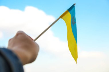 Defocus Ukraine flag. Large national symbol fluttering in blue sky. Support and help Ukraine, Independence Constitution Day, National holiday. Hand holding flag. Military. Closeup. Out of focus.