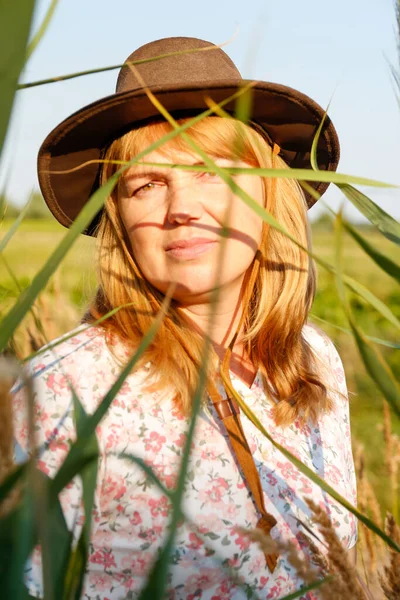 Defocus closeup outside portrait of beautiful young blonde woman near reed and pampas grass. Plant art shadows. Cowgirl on meadow. Mental health, silence. Countryside, wellness. Out of focus.
