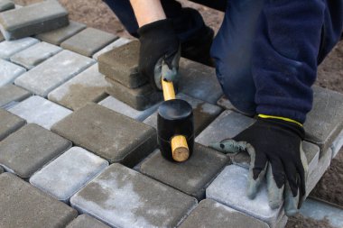 Defocus Paver ustası. İnsan katman katman taş döşeyebilir. Profesyonel kaldırım işçisi tarafından kaldırım taşı döşenmiş. Kauçuk çekiçle beton kaldırım blokları döşeyen işçilerin elleri. Odaklanamıyorum.