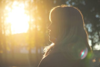 Defocus close-up silhouette of woman looking at sunrise. Mental health, hope, happiness concept. Dream autumn. Peace lifestyle. Open mind, new goals and decisions. Sunlight, sunset. Out of focus.