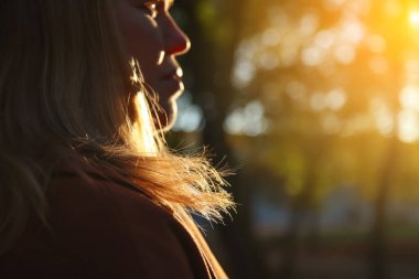 Defocus silhouette back view of woman looking at sunset. Mental health, hope, happiness concept. Peace lifestyle. Open mind, new goals and decisions. Sunlight in fall park or forest. Out of focus.