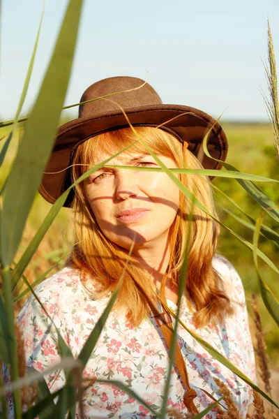 Defocus closeup outdoor portrait of beautiful young blonde woman near reed and pampas grass. Plant art shadows. Cowgirl on meadow. Mental health, silence. Countryside, wellness. Out of focus.