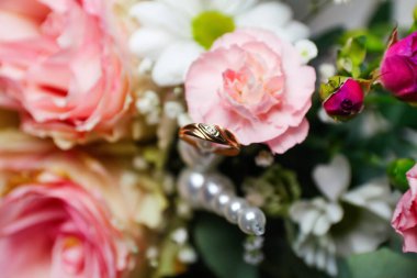 Defocus one golden wedding ring. Pink flowers and two golden wedding rings on white background. wedding rings on the rose. Out of focus.