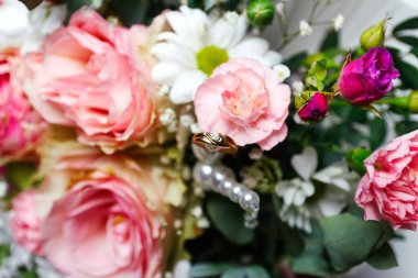 Defocus one golden wedding ring. Pink flowers and two golden wedding rings on white background. wedding rings on the rose. Copy space. Out of focus.