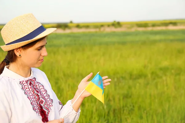 Defocus young ukrainian woman portrait. Meadow nature background. Showing ukrainian flag. Smiling ukrainian girl showing gesture love. Vyshyvanka. Invitation Ukraine. Out of focus.