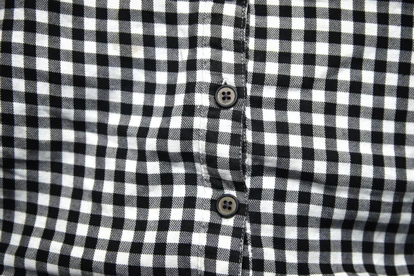 Defocus black and white shirt. Gingham tablecloth back pattern. Fragment of a wrinkled squared black and white shirt cloth fabric as a background texture. Out of focus.