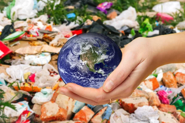 Defocus female hand holding planet globe on garbage background. Environmental protection concept. Earth in hands. Save of Earth. Elements of this image furnished by NASA. Out of focus.