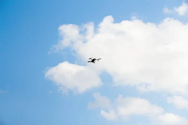 Defocus war drone. Drone flying in a blue sky. The black army unmanned aerial vehicle with four propellers and blades is on the blue sky background. Out of focus.