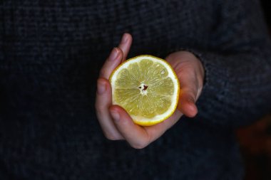 Sarı dilimli limon meyvesi tutan defocus kadın eli. Beyaz arka planda limon dilimi tutan eller. - Yakın çekim. Koyu gri arka plan. Odaklanamıyorum.