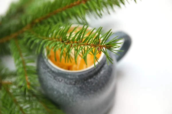 緑の天然モミの木の枝の背景にあるオレンジ色のみかんやみかんの葉のクローズアップマグカップに焦点を当ててください 創造的なクリスマスの熱い飲み物 休日の気分 アートクリスマスのコンセプト コピースペース 集中できない — ストック写真
