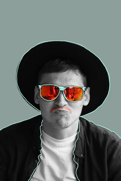 Funny man. Smiling fashion man. Portrait of handsome smiling stylish hipster lambersexual model. Man dressed in red polarization sunglasses and hat. Fashion male on gray background. Red moustache.