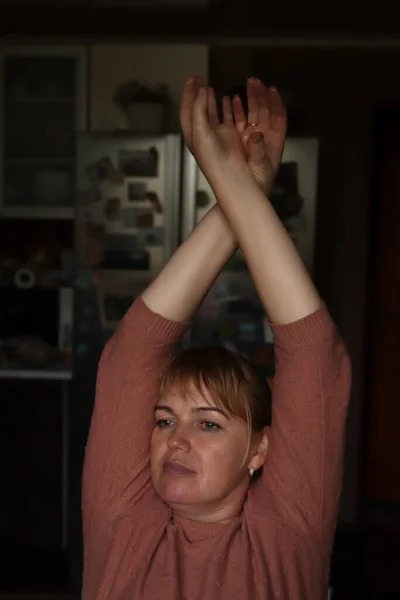 Defocus woman against dark indoor background, closeup on hands. Beauty gesturing woman's hands with care. Wellness. Out of focus.