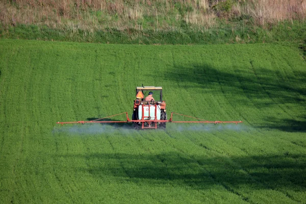 Farm tractor spraying field before planting — Stock Photo, Image