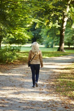 Elegant woman walking in the park clipart