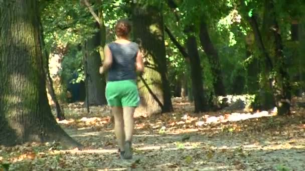 Mujer joven corre en parque público — Vídeo de stock