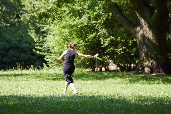 Junge Frau spielt Frisbee — Stockfoto