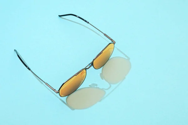 Okulary przeciwlotnicze na niebieskim tle. Modne okulary przeciwsłoneczne ze światłem słonecznym do koncepcji lata. Złoto gradientu na wizjerze soczewki lustra — Zdjęcie stockowe