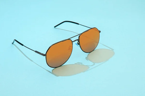 Occhiali da sole Aviator su sfondo blu. Occhiali da sole alla moda con luce solare per il concetto estivo. Gradiente dorato sull'aviatore con lente a specchio. — Foto Stock