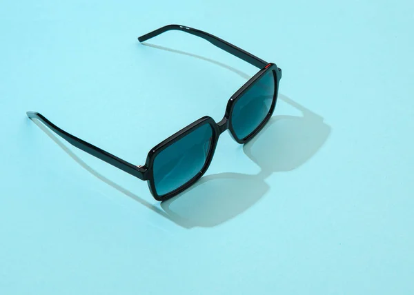 Gafas de sol de verano para mujer sobre fondo azul pastel a la luz del sol. Gafas de sol modernas y elegantes para unas hermosas vacaciones de vacaciones. Moda gafas femeninas. —  Fotos de Stock