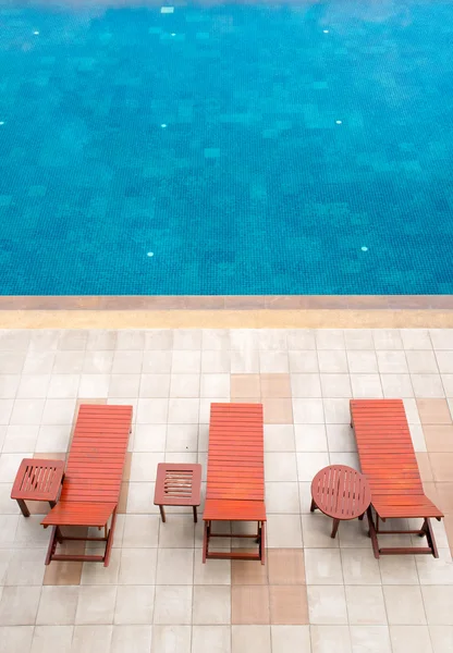 Transats au bord de la piscine à côté de la piscine bleue — Photo