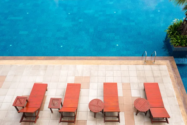 Transats au bord de la piscine à côté de la piscine bleue — Photo