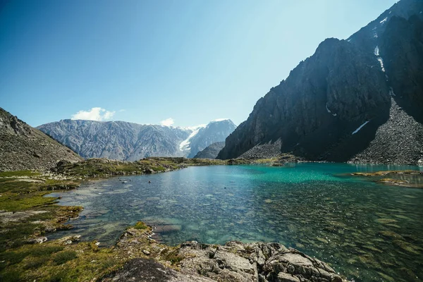 Sunny relaxing landscape with azure glacial lake in sunlight. Meditative ripple and many reflected lights on turquoise clear water surface of mountain lake. Beautiful scenery with lake and glacier.