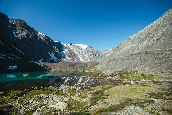 雪山映衬在冰湖清澈的水中 清澈的天空下 美丽的阳光普照 山湖水面上的冰川反射 岩石上的雪反映在高山湖中 — 图库照片