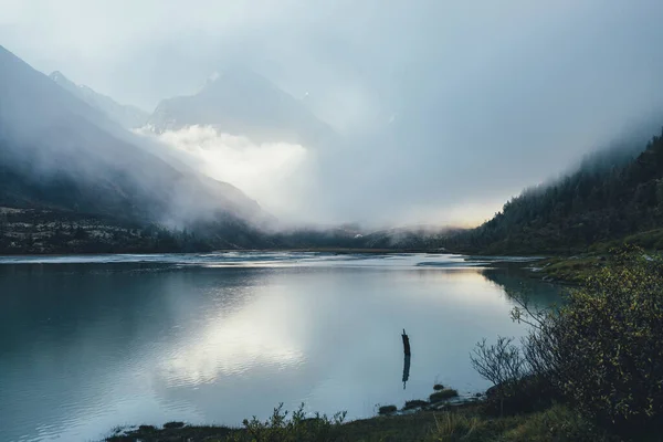 Sfeervol Alpenlandschap Met Bergmeer Hoge Besneeuwde Berg Dichte Lage Wolken — Stockfoto