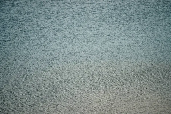 Texture of dark blue calm water of lake. Meditative ripples on water surface. Nature minimal background of deep blue lake. Natural backdrop of clear dark turquoise water. Full frame of lake fragment.