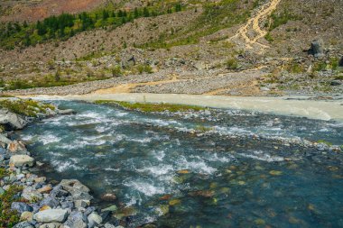 Üç nehrin birleştiği çok renkli dağ manzarası. Aynı kanalda üç nehir bulunan güneşli ve canlı bir manzara. Aynı şeritteki üç dağ nehrinin manzarası. Alışılmadık bir nehir ağzı.